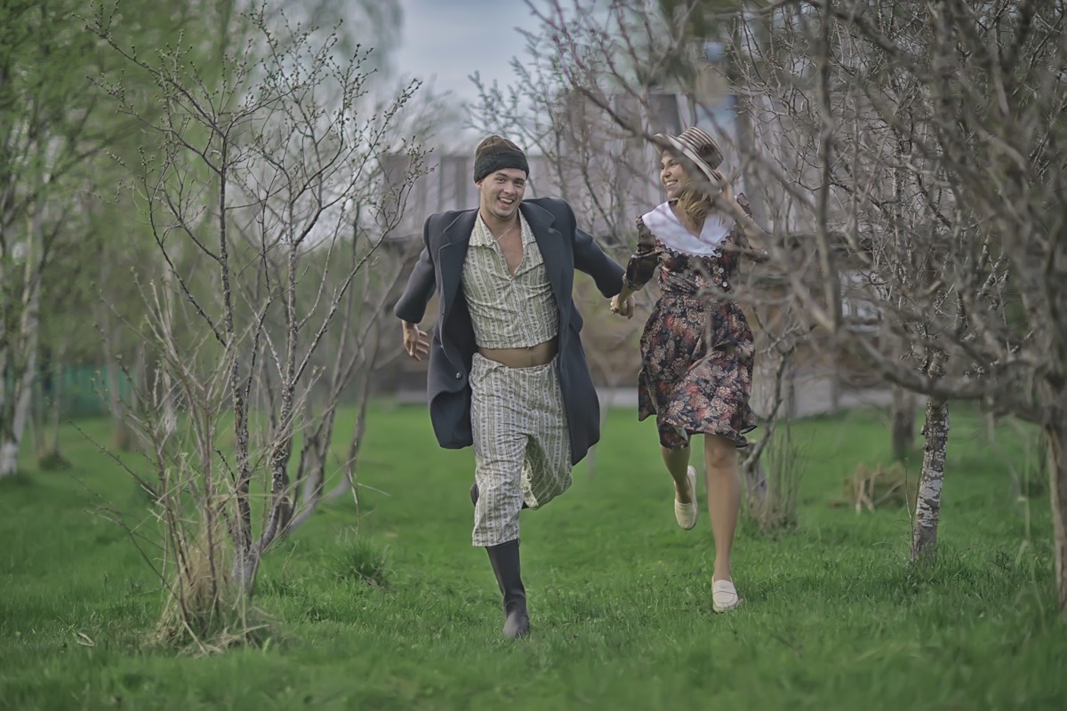 A vintage couple running through a spring orchard